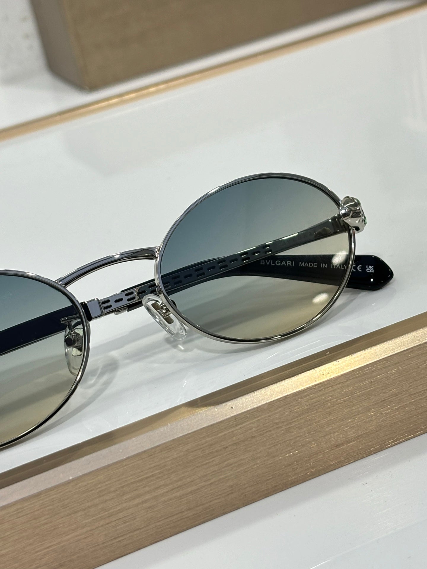 Round sunglasses with silver metal frame, blue lenses, and engraved temple detail