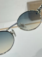 Close-up of round sunglasses frame with blue-tinted lens and silver hinge