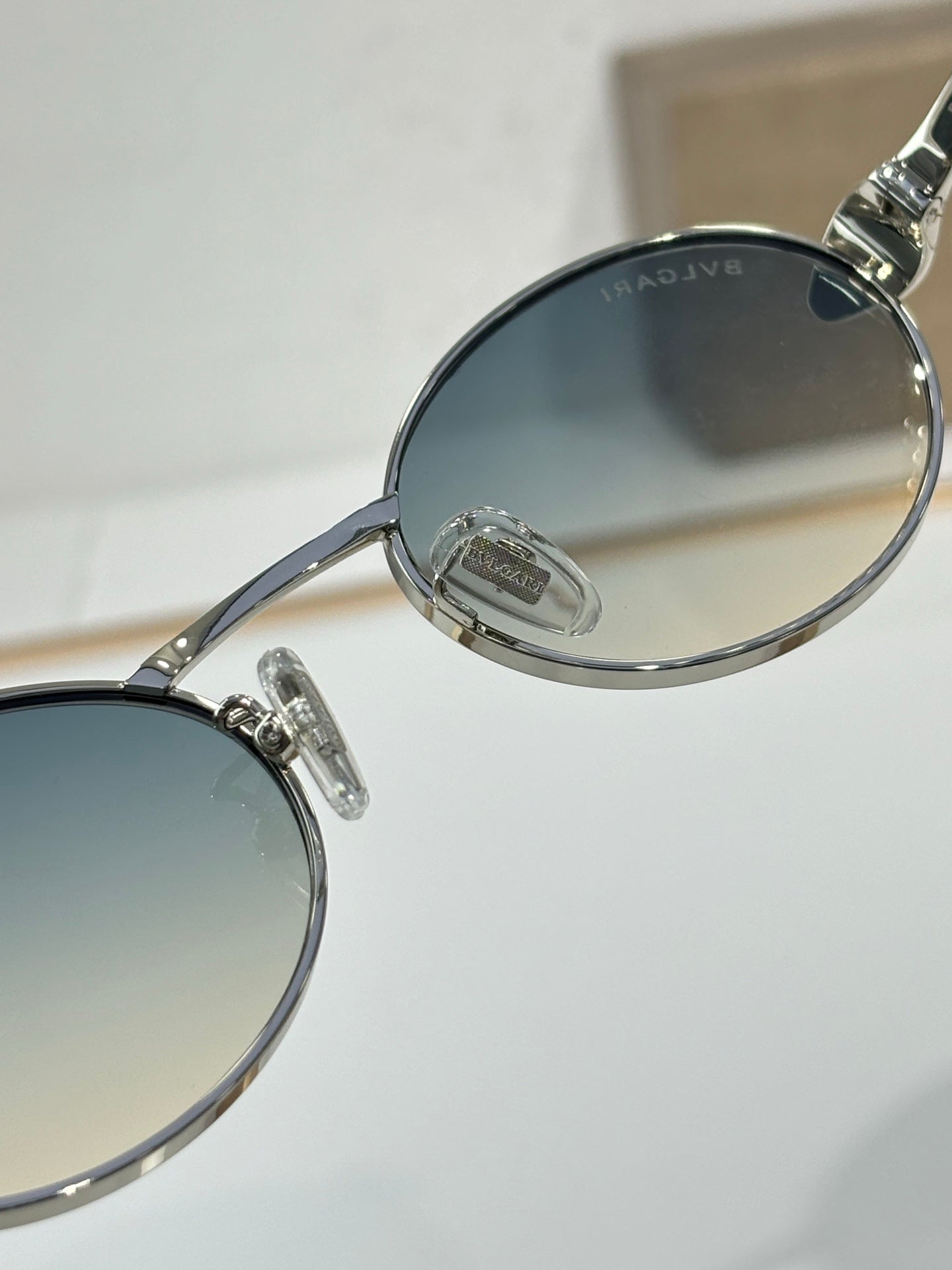 Close-up of round sunglasses frame with blue-tinted lens and silver hinge