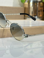 Round sunglasses with silver metal frame, blue lenses, and black temple