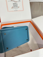 Blue leather mini handbag back panel with snap studs; corner eyelets visible.