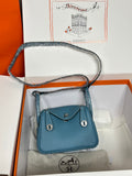 Blue leather mini handbag with top handle and crossbody strap, front flap and clasp.