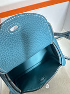 Blue leather mini handbag close-up with interior zipper pocket and metal snap button.