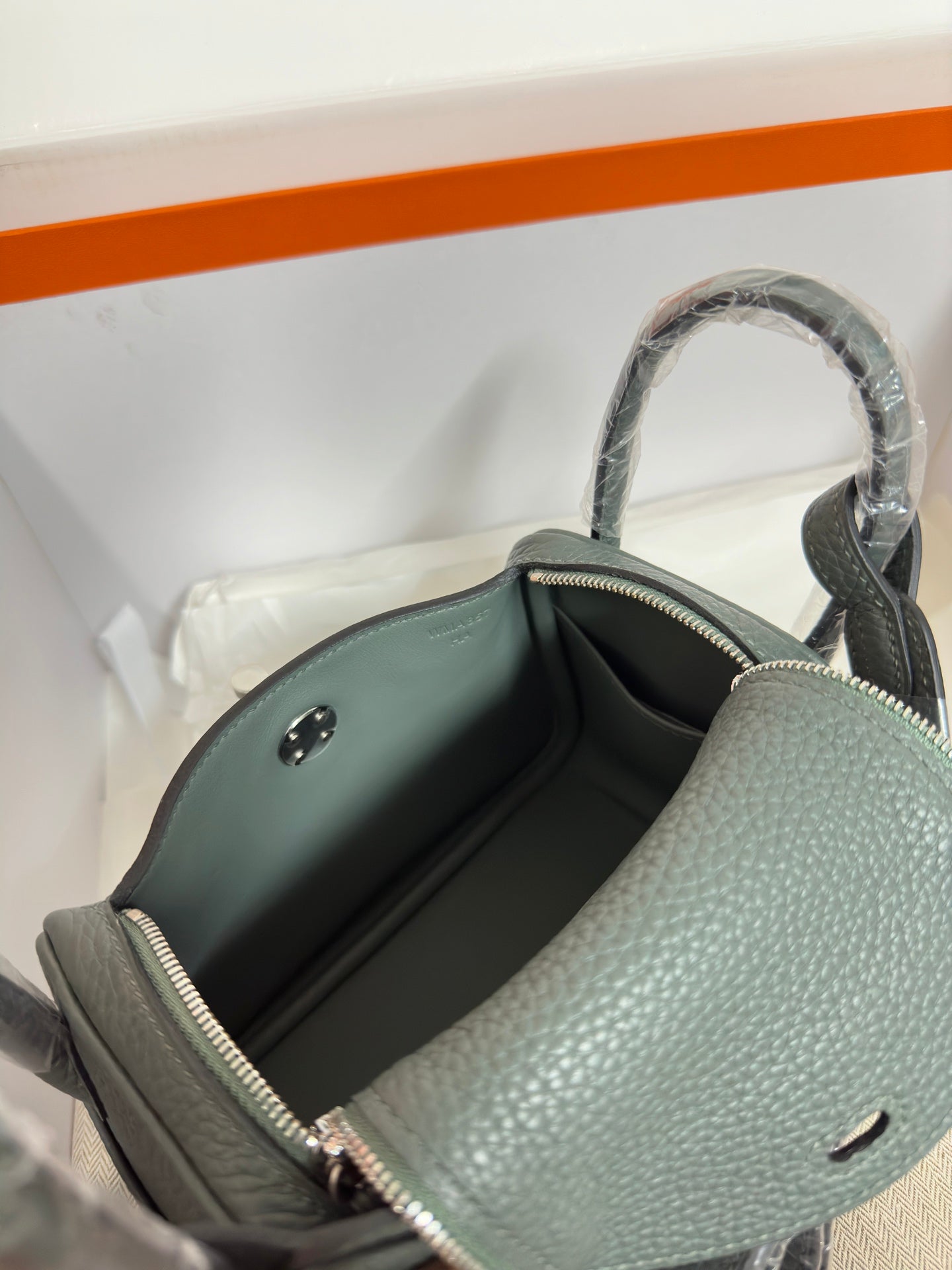 Hermes bag interior close-up, dark lining, gold zipper, pebbled leather side wall.