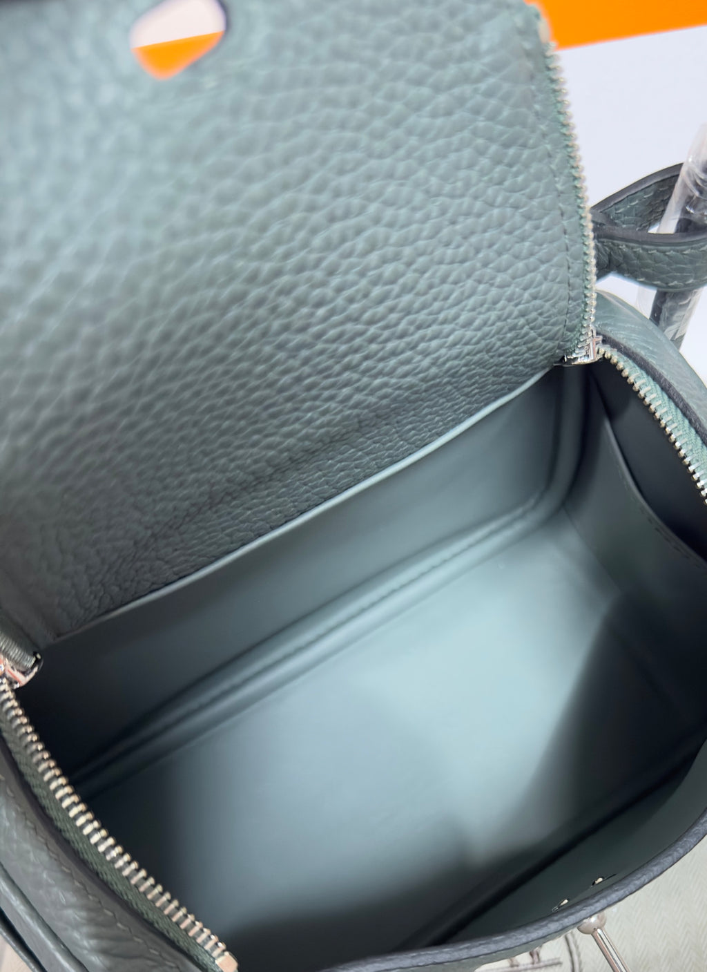 Hermes bag interior close-up, dark lining and gold zipper edge, pebbled leather top.