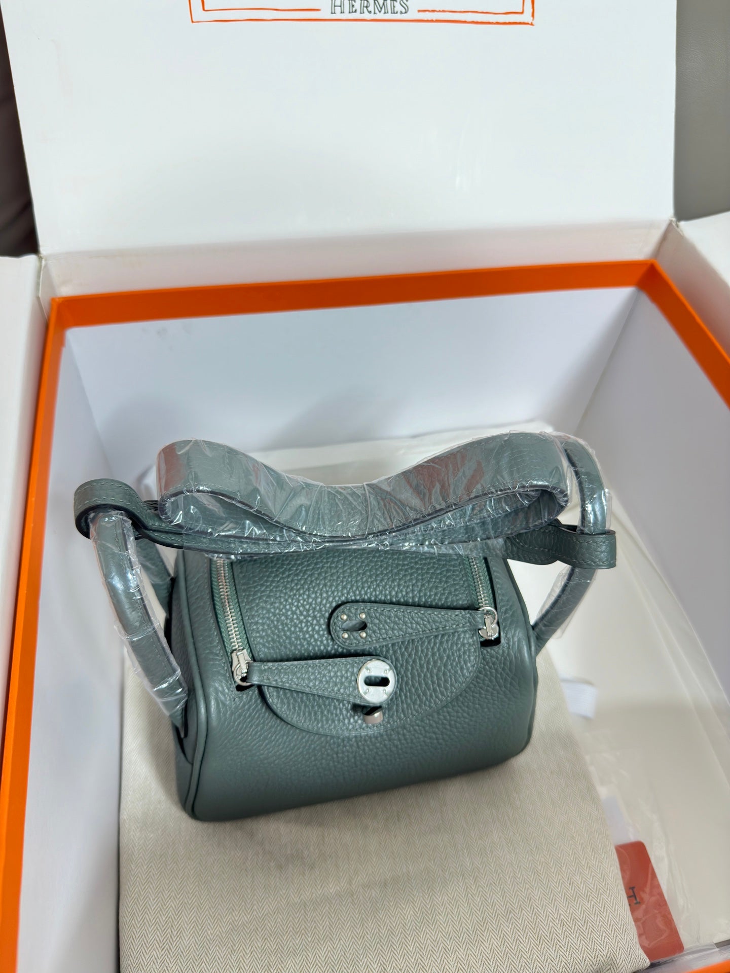 Hermes bag, dark teal pebbled leather, crossbody strap and top handle, boxed display.