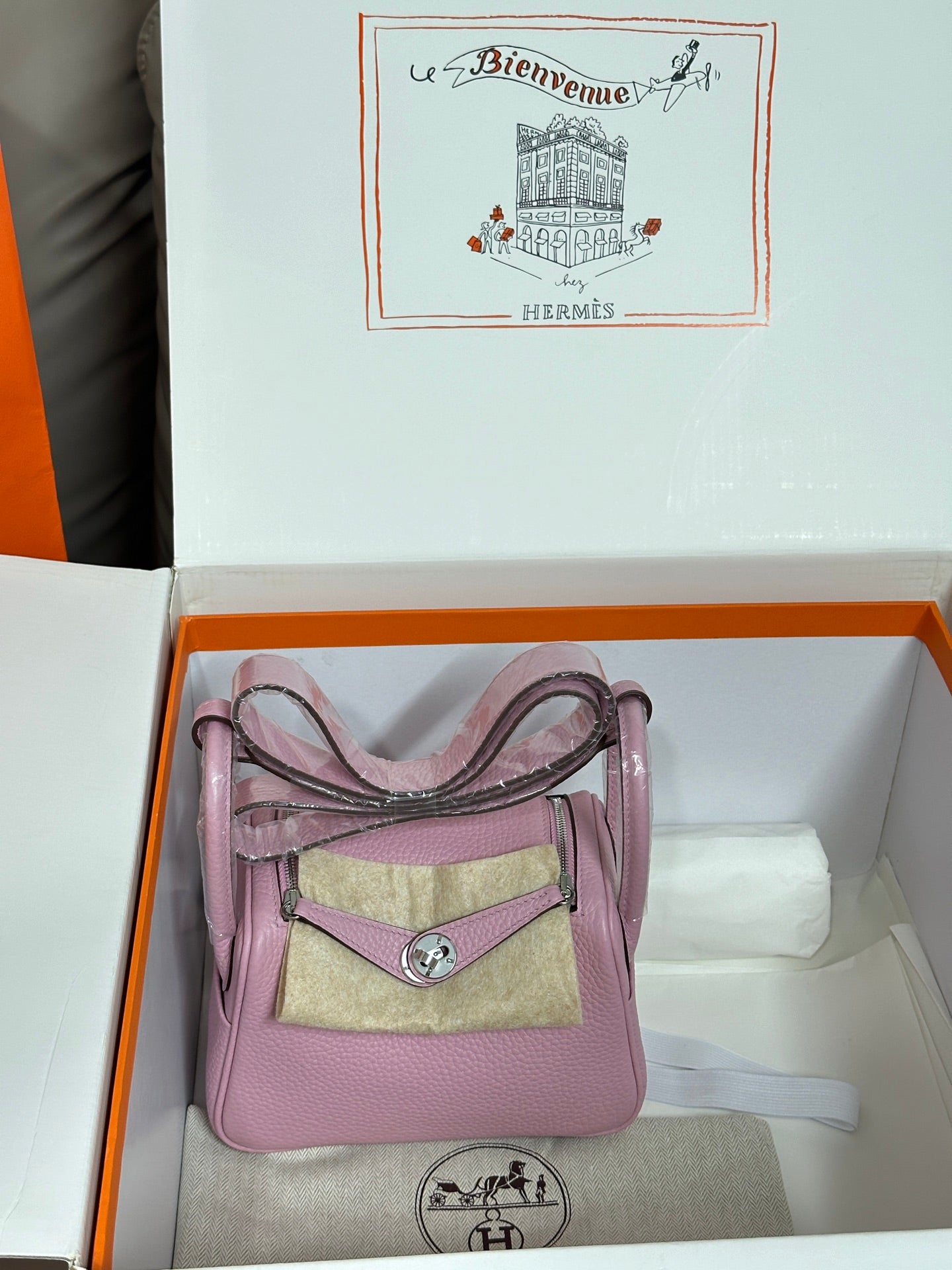 Pink leather mini handbag with top handles and small front pouch detail.