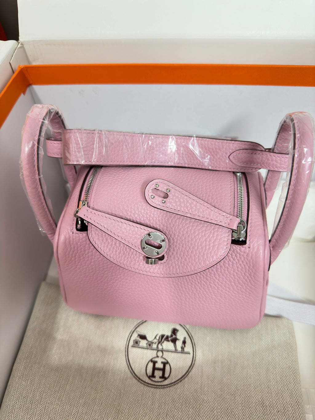 Pink leather handbag with detachable strap, front flap and silver clasp.