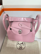 Pink leather handbag with detachable strap, front flap and silver clasp.