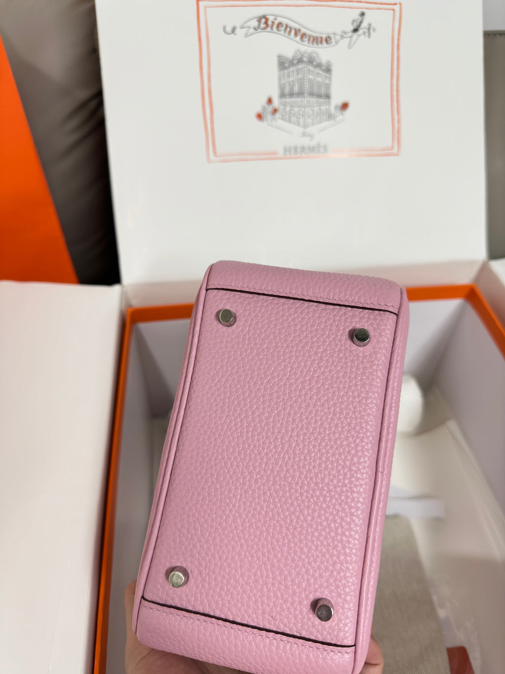 Pink leather handbag back panel with two snap buttons and textured grain.
