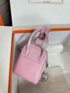Pink leather handbag with side profile, top handle and silver strap hardware.