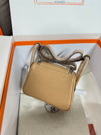 Hermes beige leather mini bag side view with top handle, front flap and metal rivets