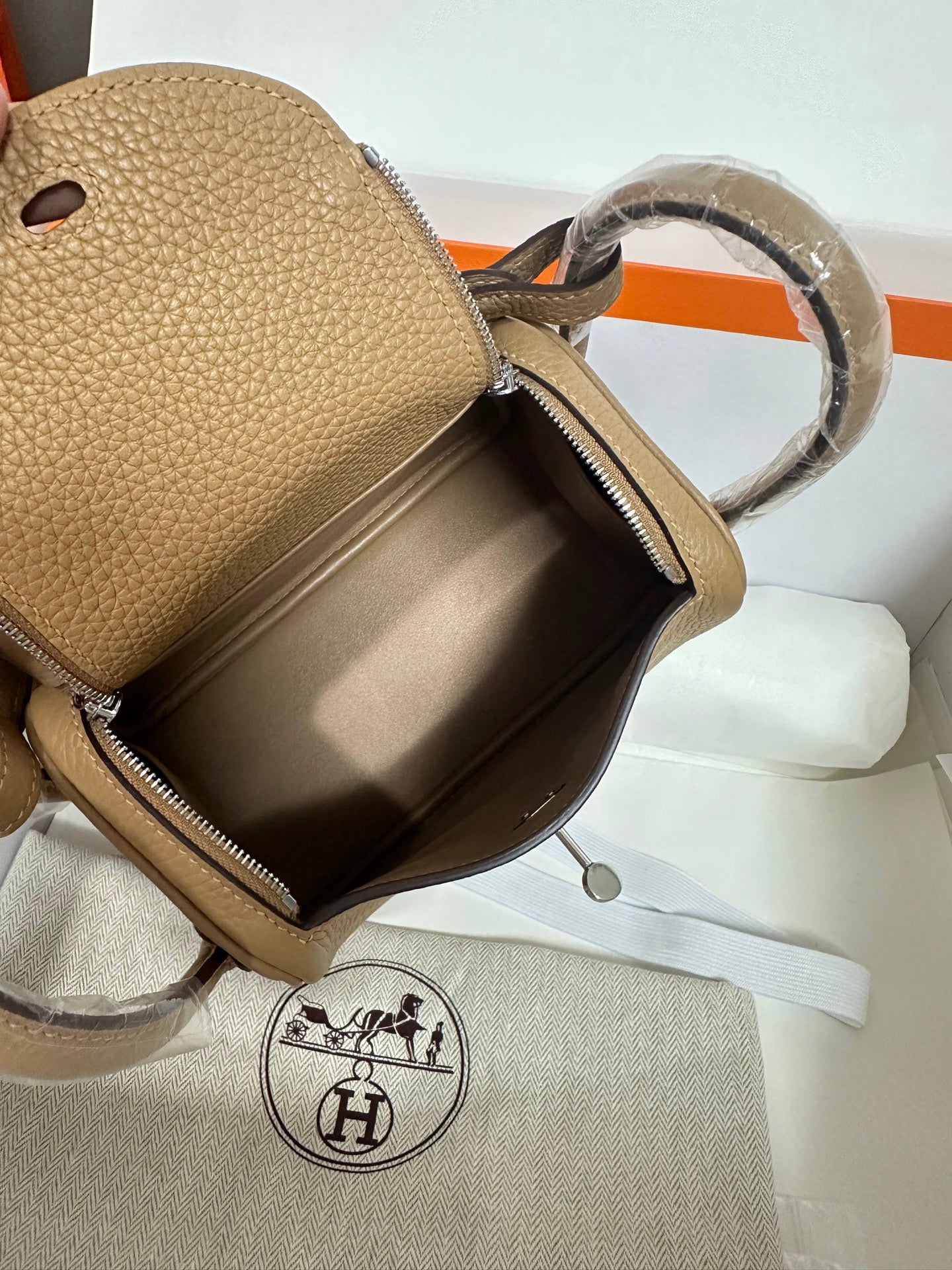 Hermes beige leather mini bag interior view with zipper opening and silver-tone lining