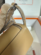 Hermes beige leather bag close-up with silver zipper and reinforced top edge