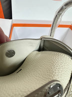 Hermes bag corner close-up with snap button and light beige textured leather