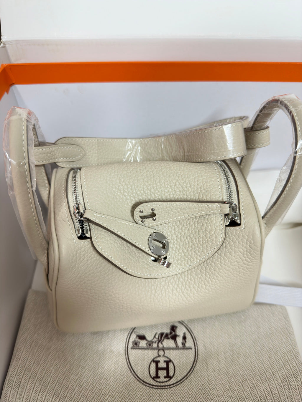 Hermes bag front view in light beige textured leather with metal logo hardware