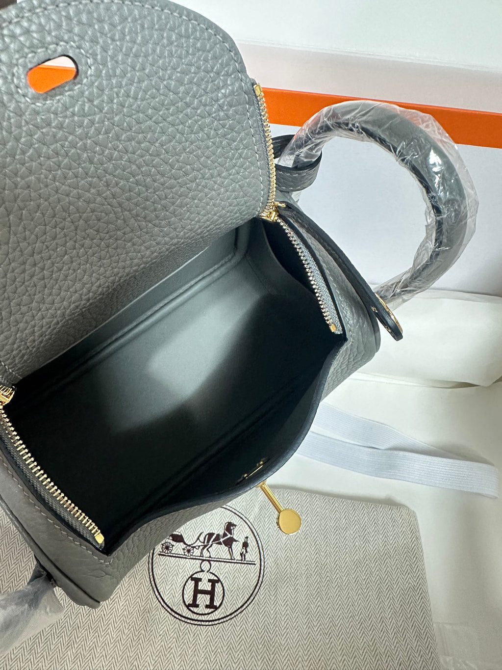 Close-up of gray leather handbag pocket with zipper detail and gold-tone hardware.