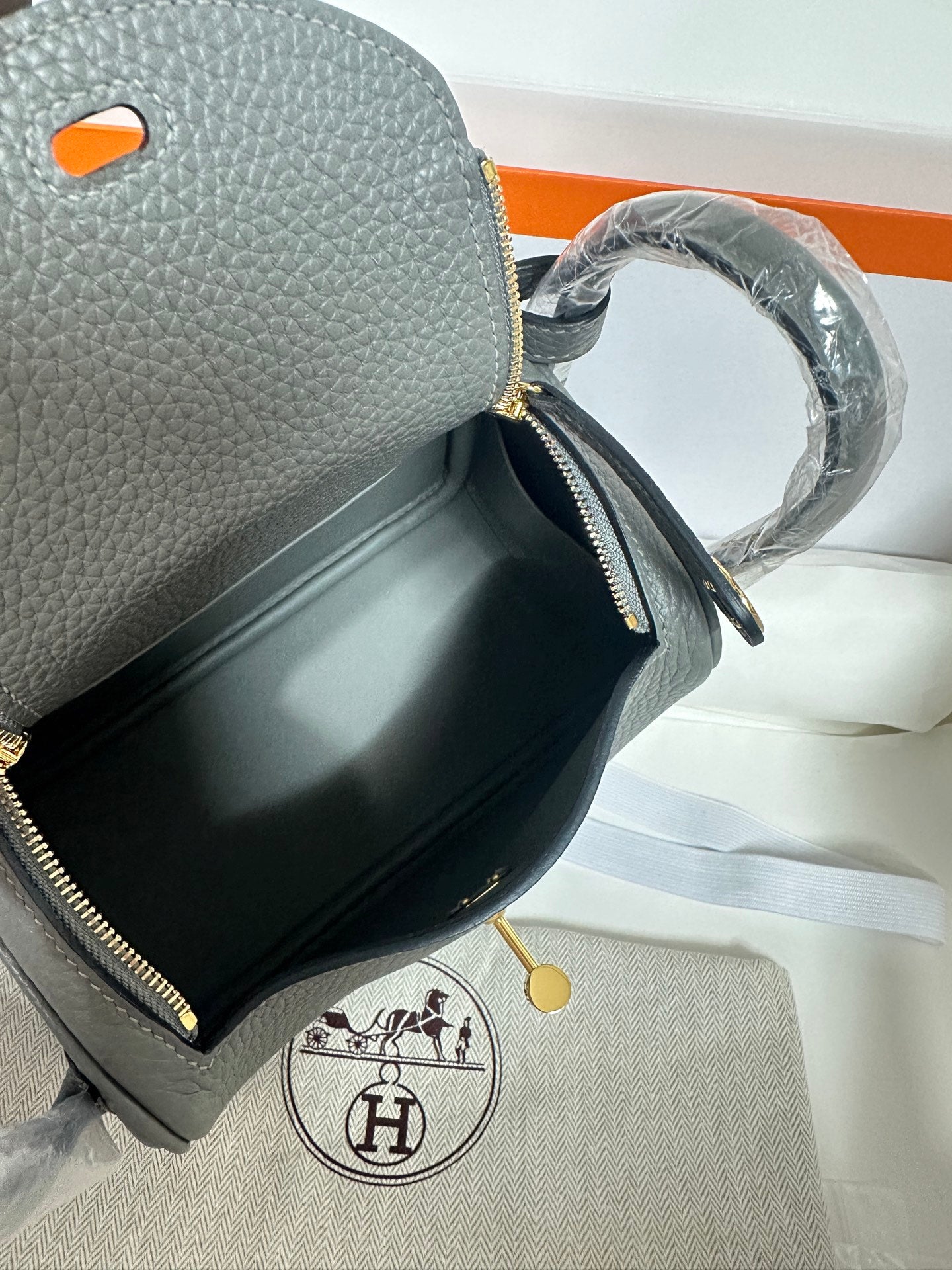 Close-up of gray leather handbag pocket with zipper detail and gold-tone hardware.
