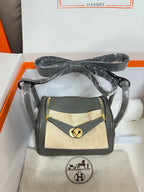 Gray leather handbag with tan canvas flap and gold-tone clasp, boxed.