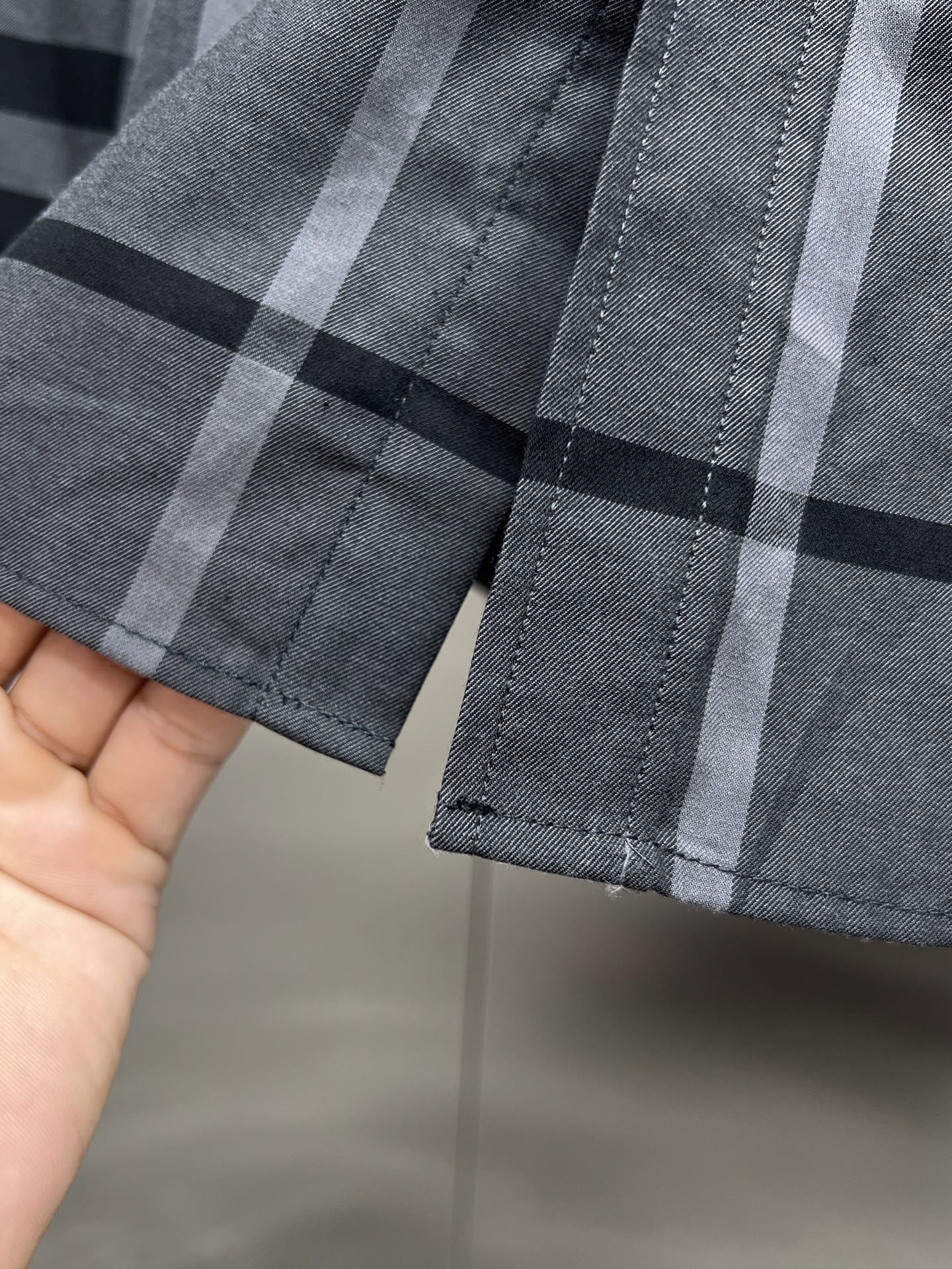 Plaid long-sleeve shirt cuff with button detail, dark and light gray checks