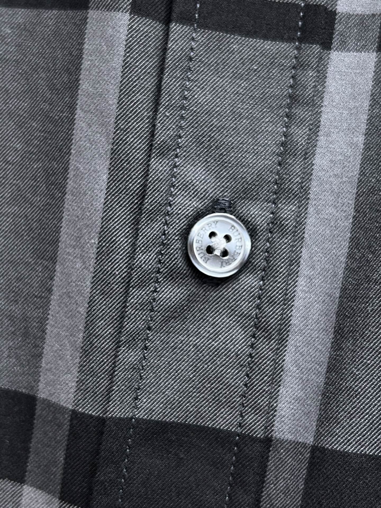 Gray and black plaid button-up shirt close-up of front button