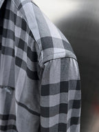 Plaid button-up shirt sleeve in gray and black check pattern, side view