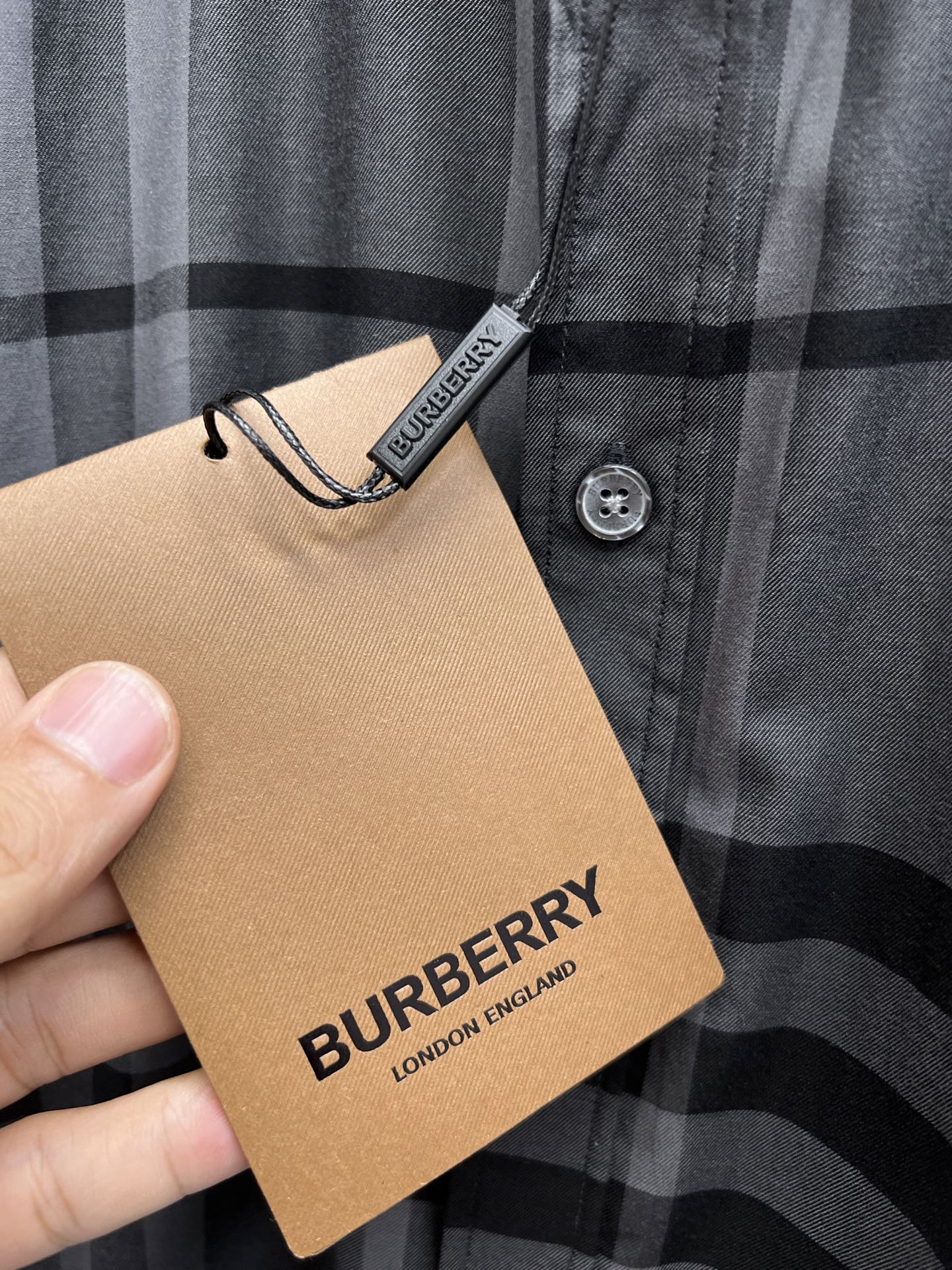 Plaid button-up shirt collar with attached Burberry hang tag and button detail