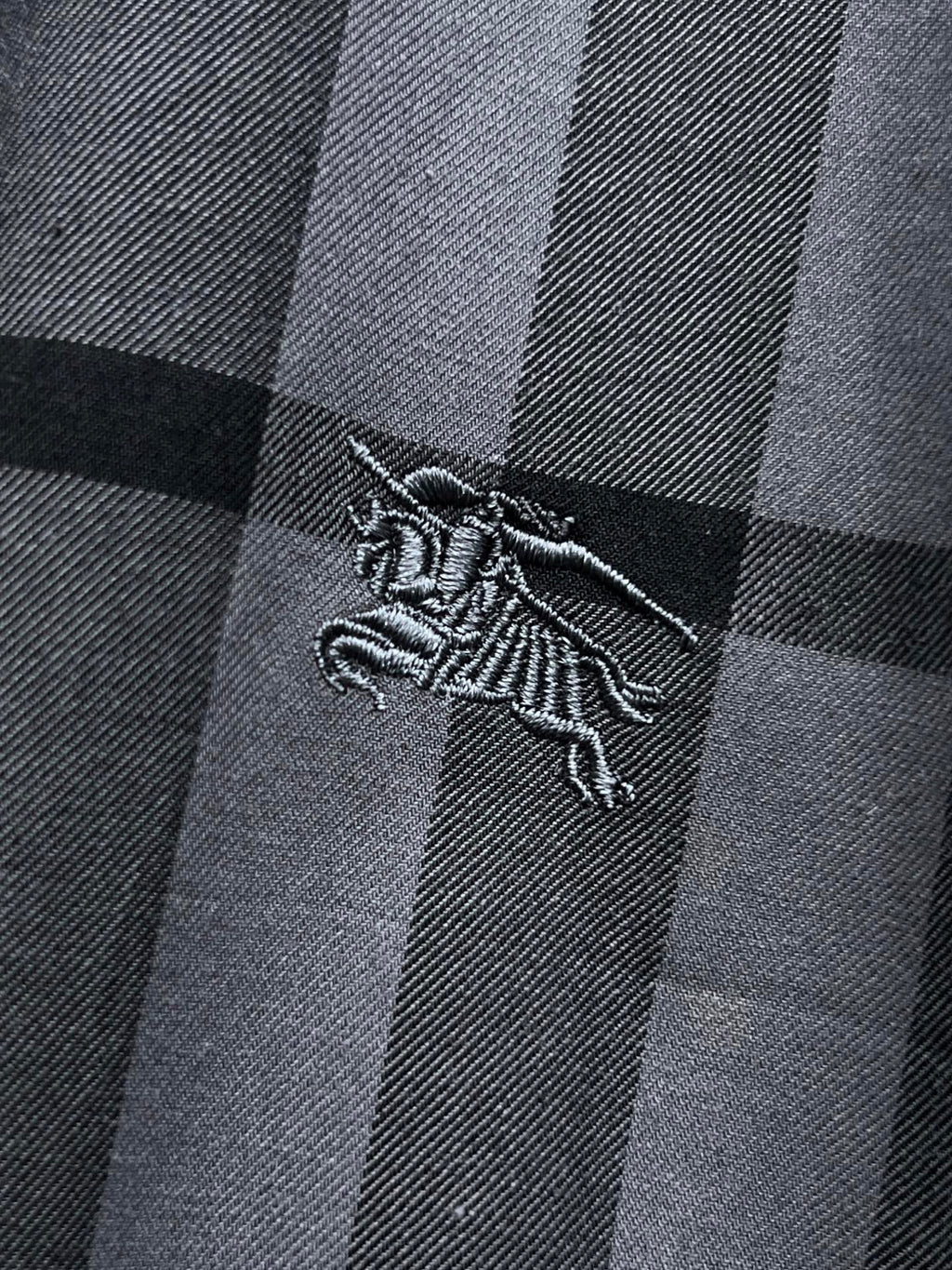 Embroidered dragon logo on gray and black plaid fabric, close-up
