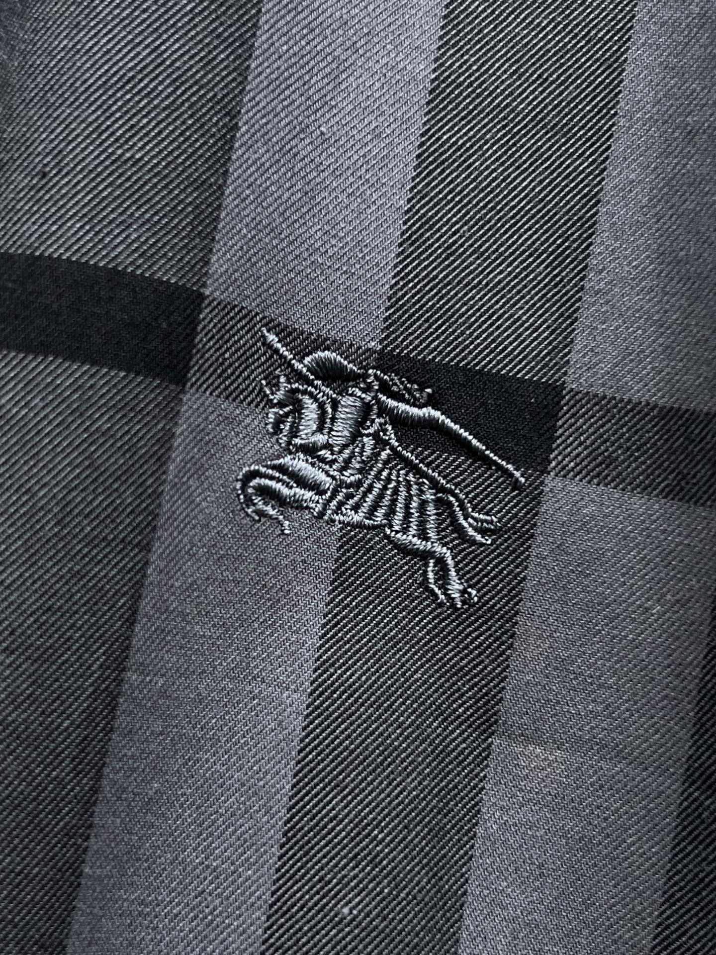 Embroidered dragon logo on gray and black plaid fabric, close-up