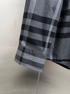 Plaid button-up shirt hem with gray and black check pattern, side view