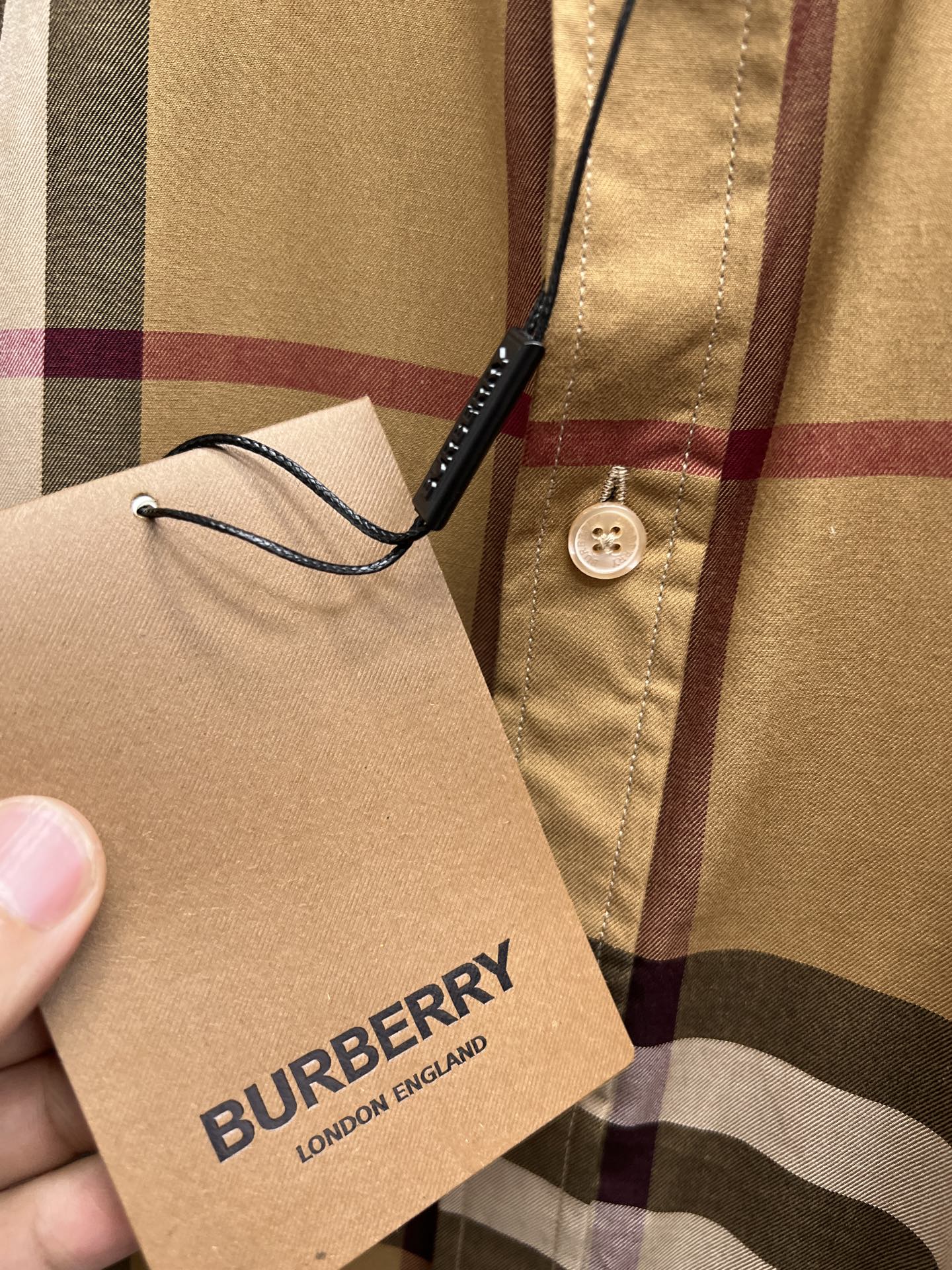 Burberry fabric tag on beige plaid shirt with button placket