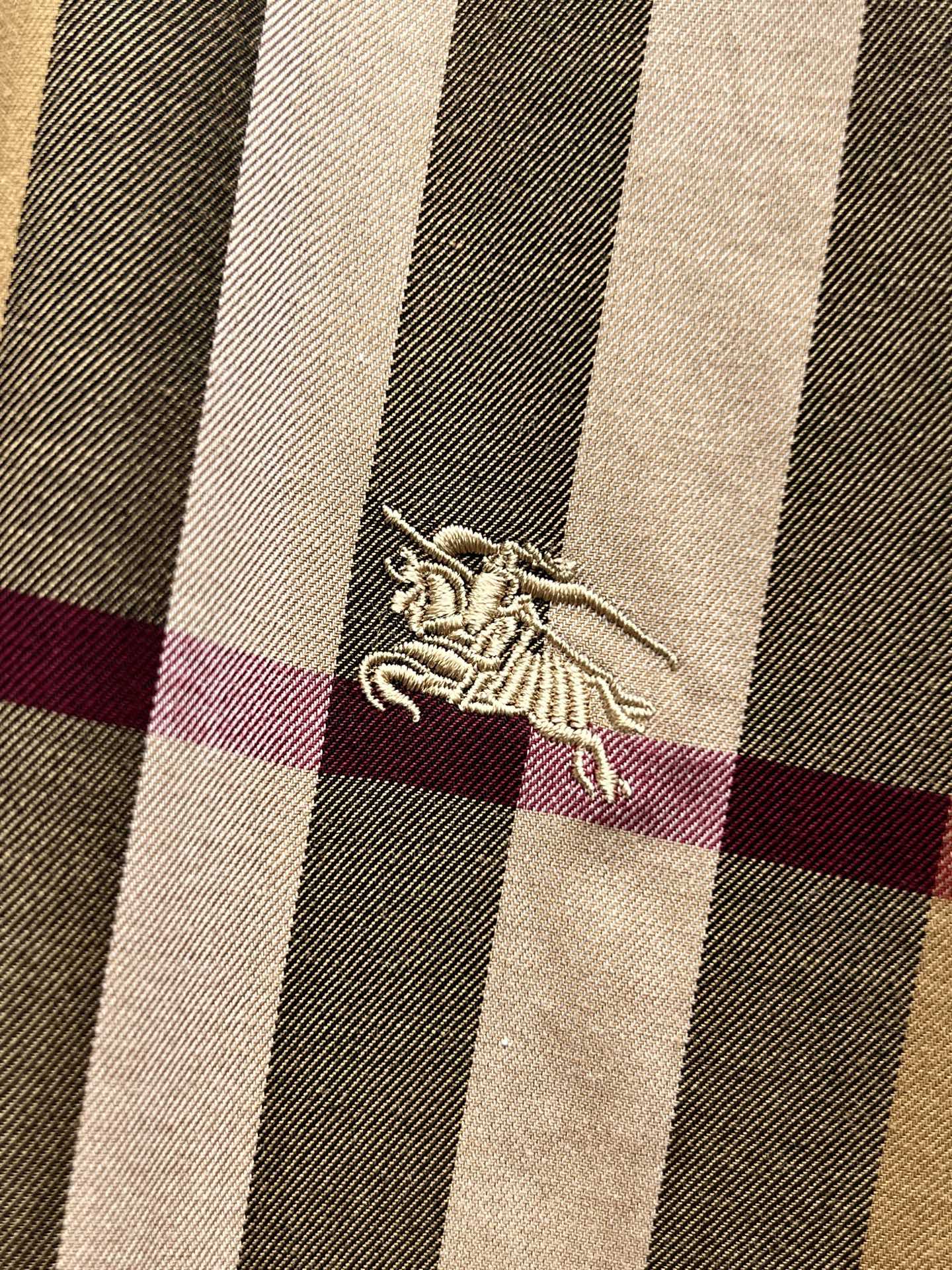 Burberry embroidered horse logo on beige, navy, and maroon plaid fabric