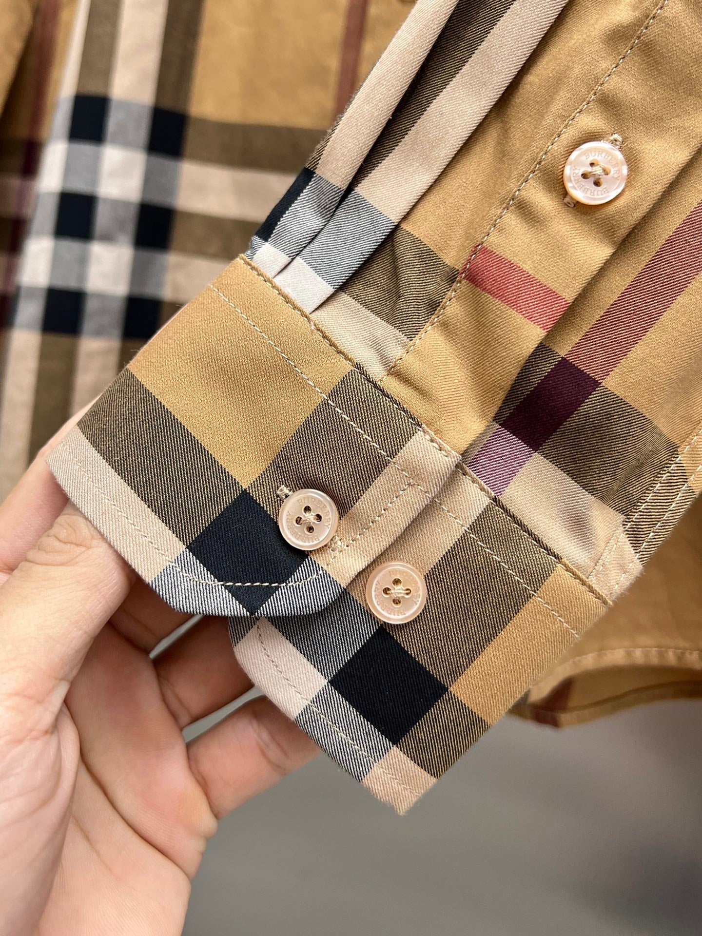 Burberry plaid buttoned placket with fabric cuff and small round buttons