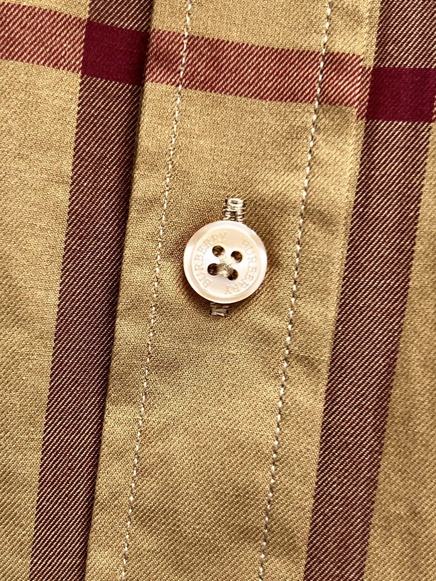 Placket buttons on beige Burberry plaid shirt, white button with four holes