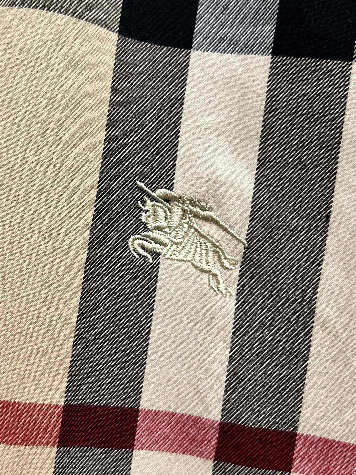 Burberry embroidered horse logo on beige and navy plaid fabric