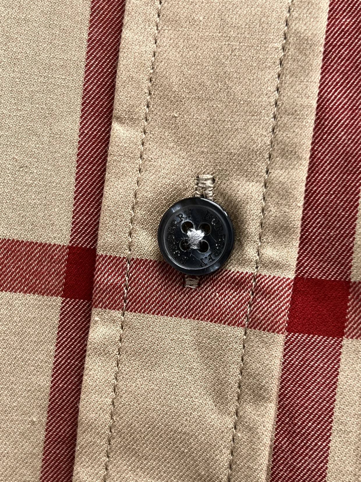 Burberry shirt button on beige, navy and red plaid fabric