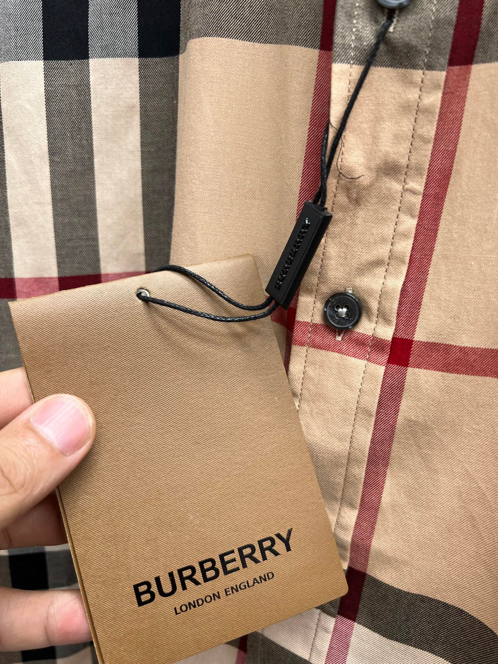 Burberry brand tag tied to beige navy red plaid long-sleeve shirt