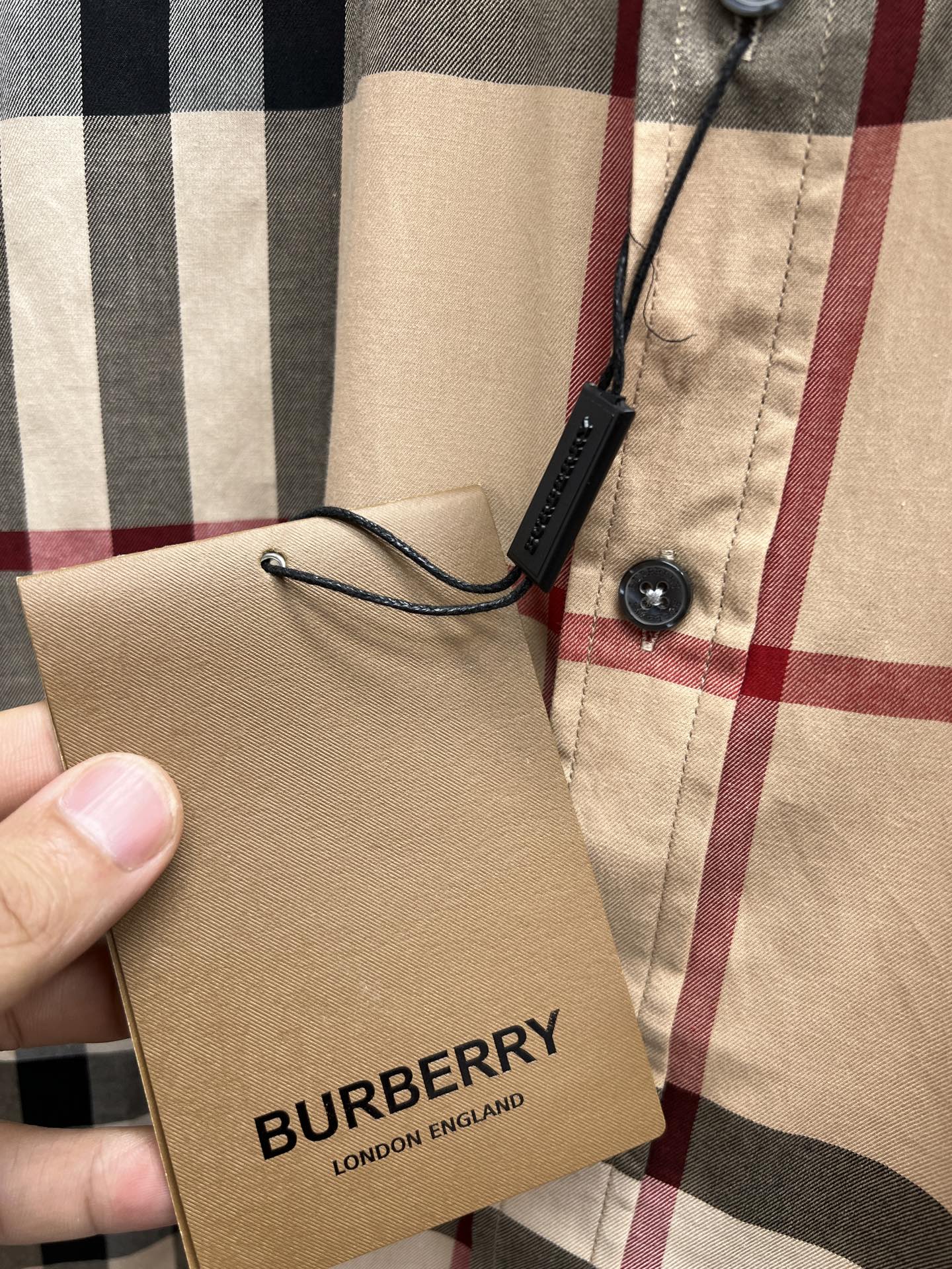 Burberry brand tag tied to beige navy red plaid long-sleeve shirt