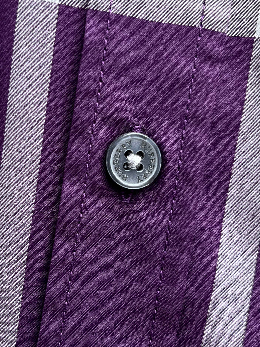 Burberry plaid shirt button detail on purple fabric with white trim