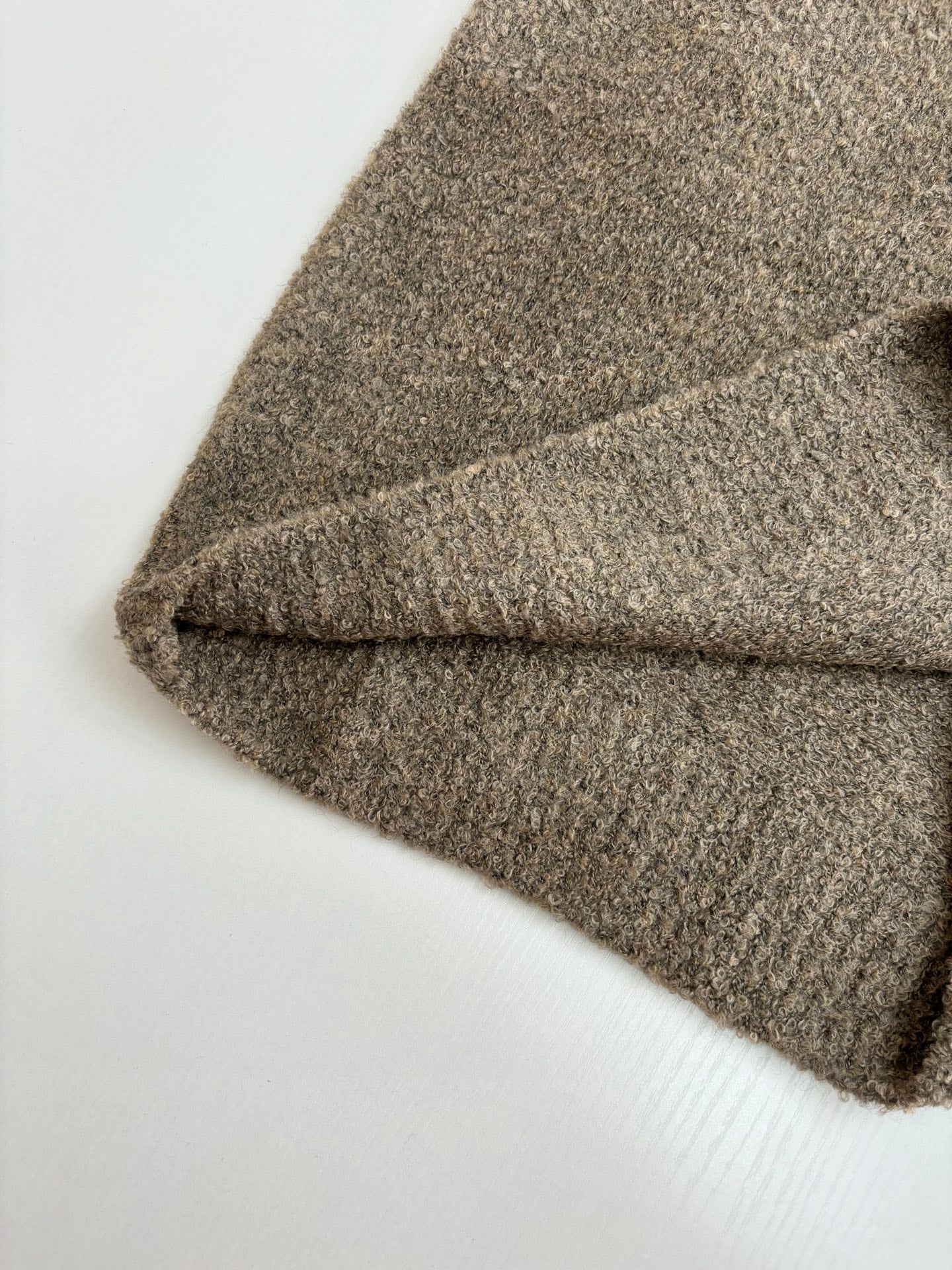 Brown knit sweater sleeve and hem detail, soft textured fabric