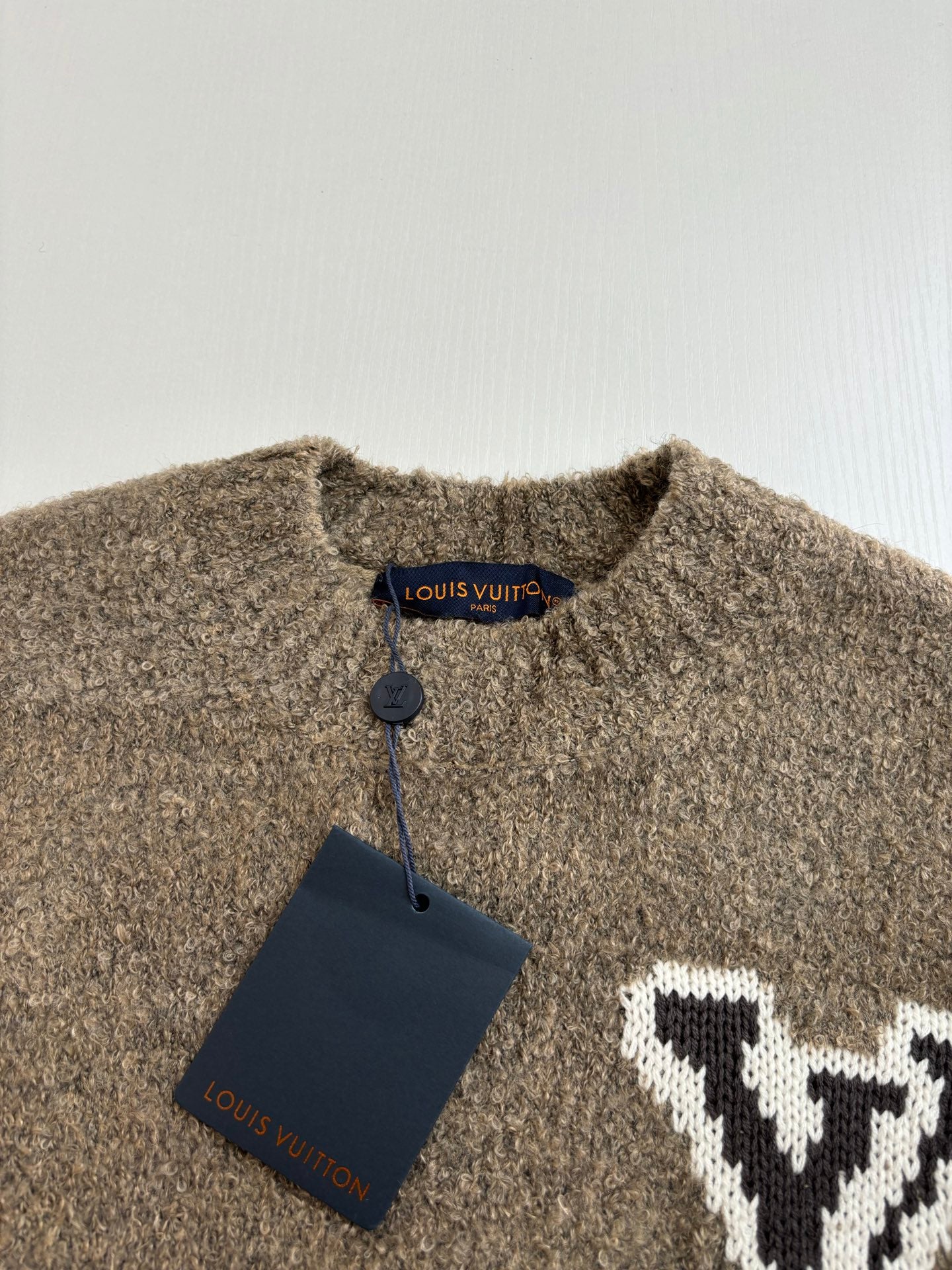 Brown knit sweater neckline with blue Louis Vuitton tag and white LV logo