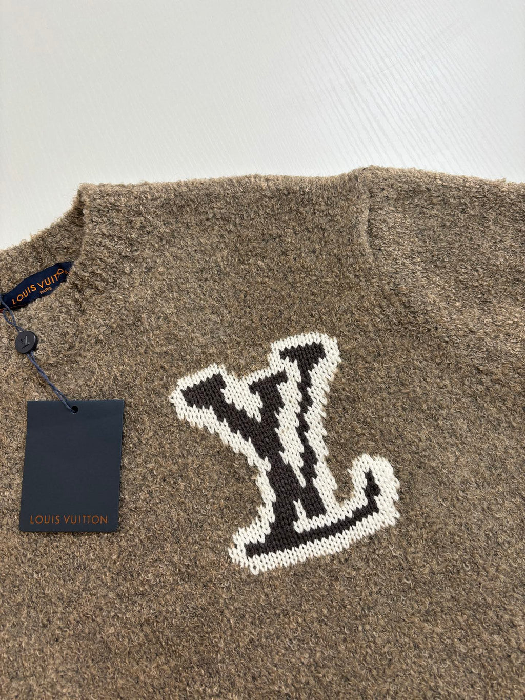 Brown knit sweater with large white LV monogram on front, close-up