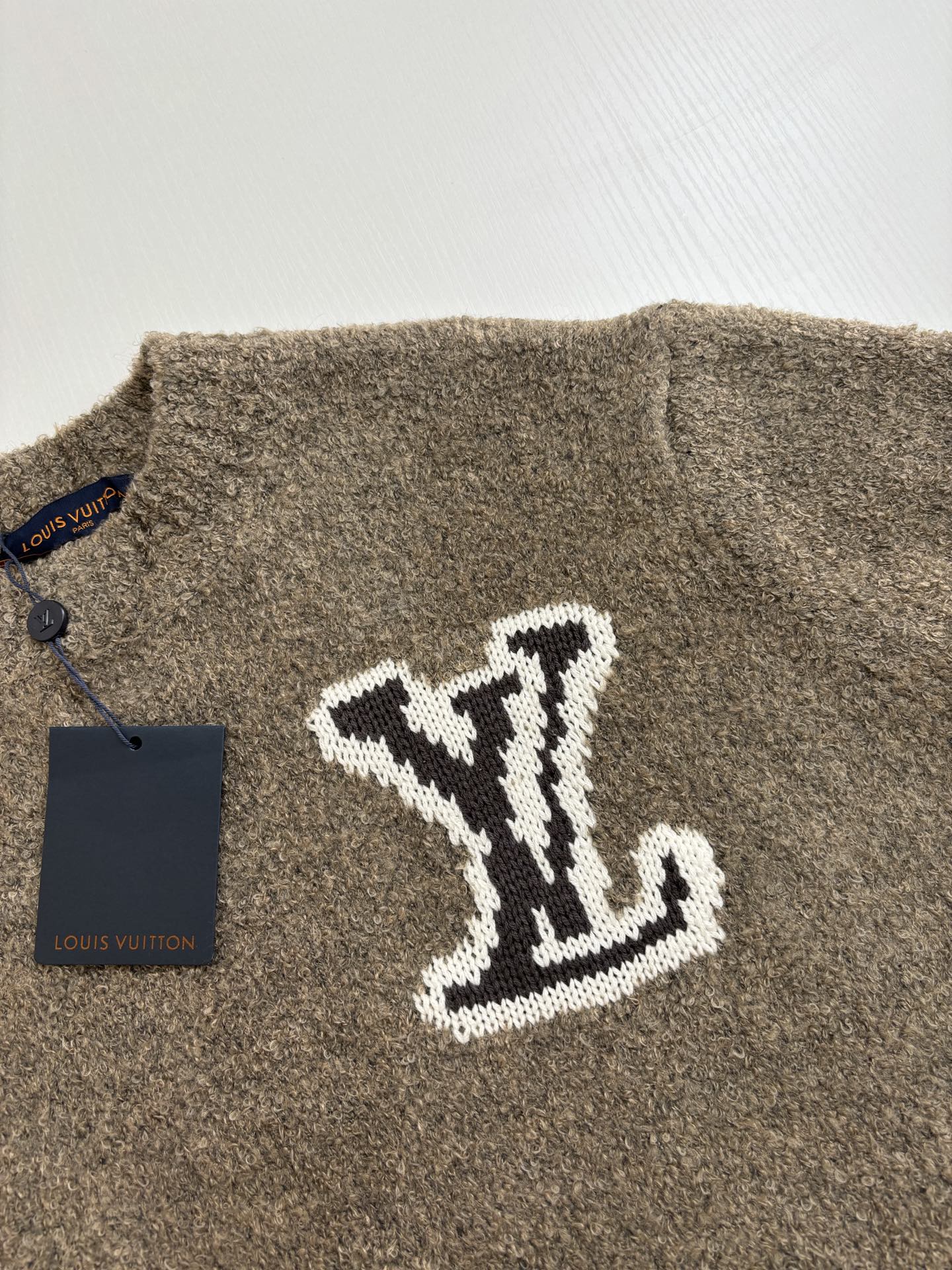 Brown knit sweater with large white LV monogram on front, close-up