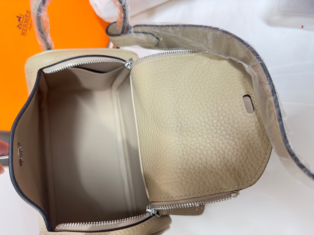 Open taupe leather handbag showing interior compartment with zip pocket and snap tab
