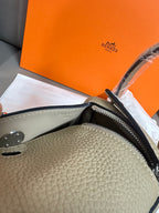 Close-up of taupe textured leather handbag edge with silver zipper hardware