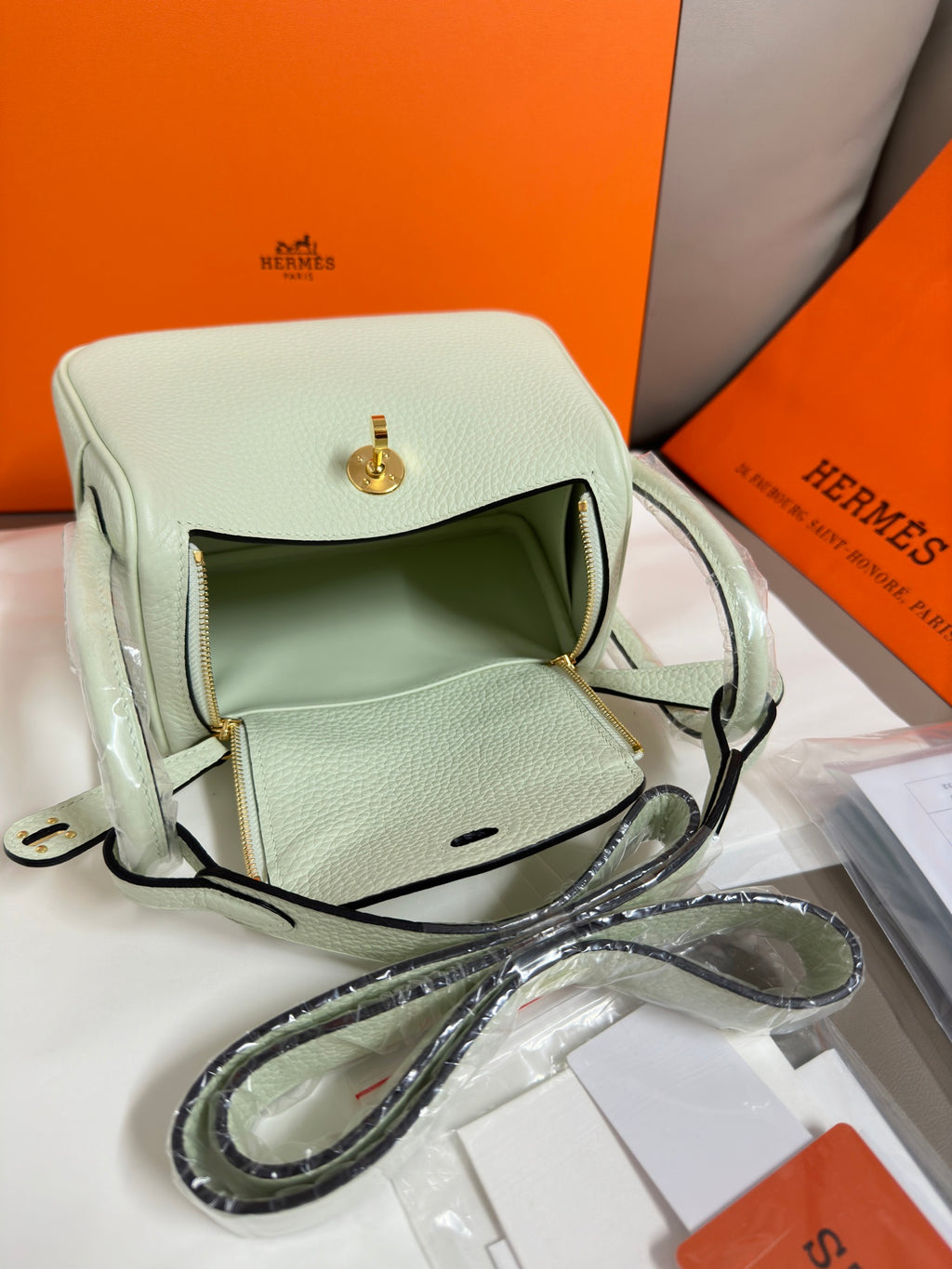 Hermes mint leather handbag with front flap, zipper pocket, and crossbody strap