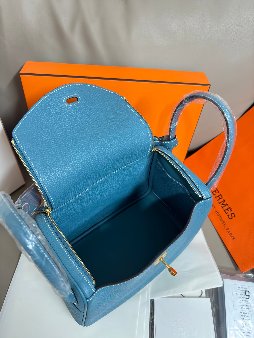 Hermes blue leather handbag with open top showing dark interior and zipper