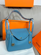 Hermes blue leather handbag with front flap, side rings, and gold-tone hardware
