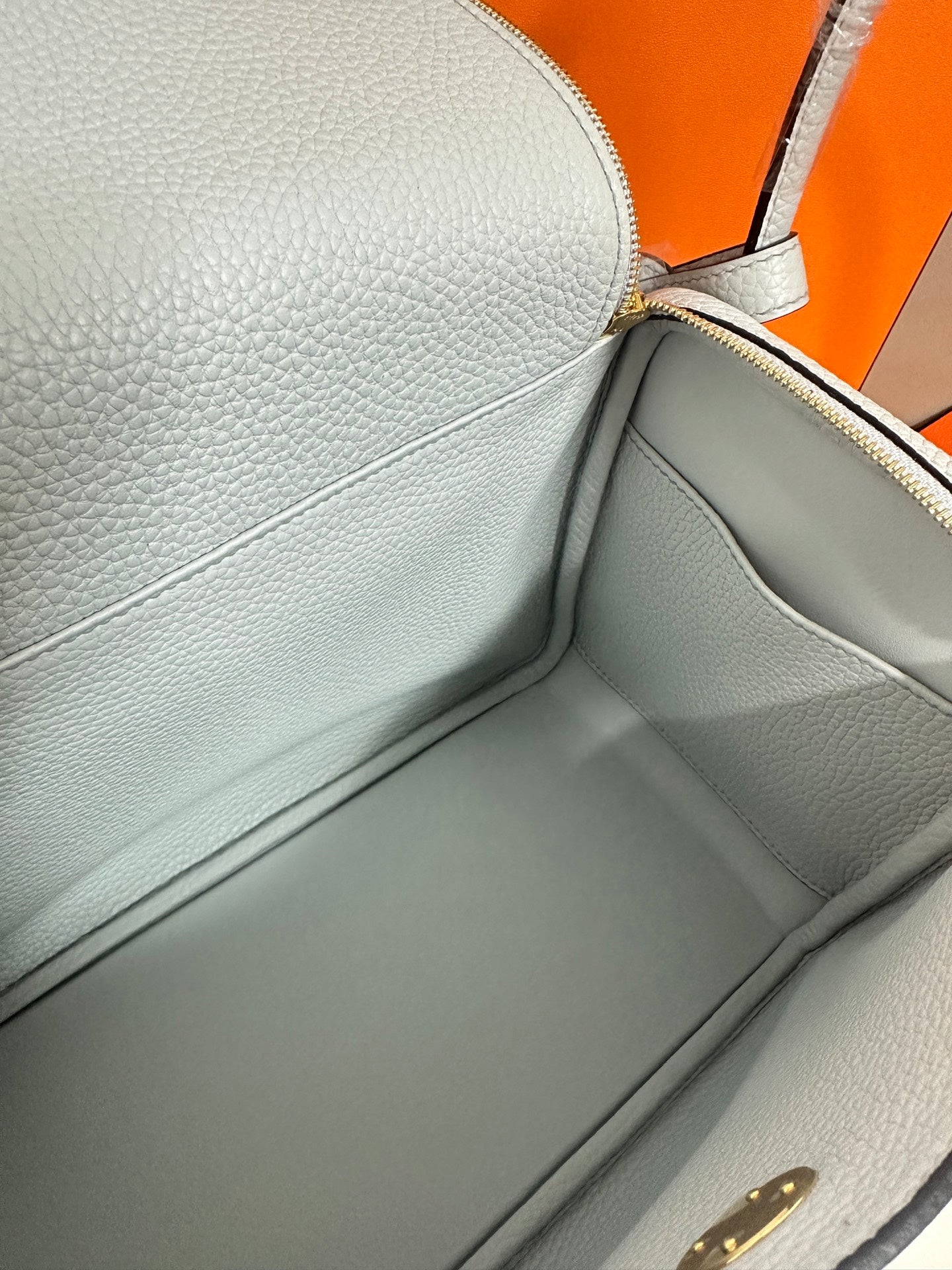 Light blue leather handbag interior view with smooth lining and zipper edge.