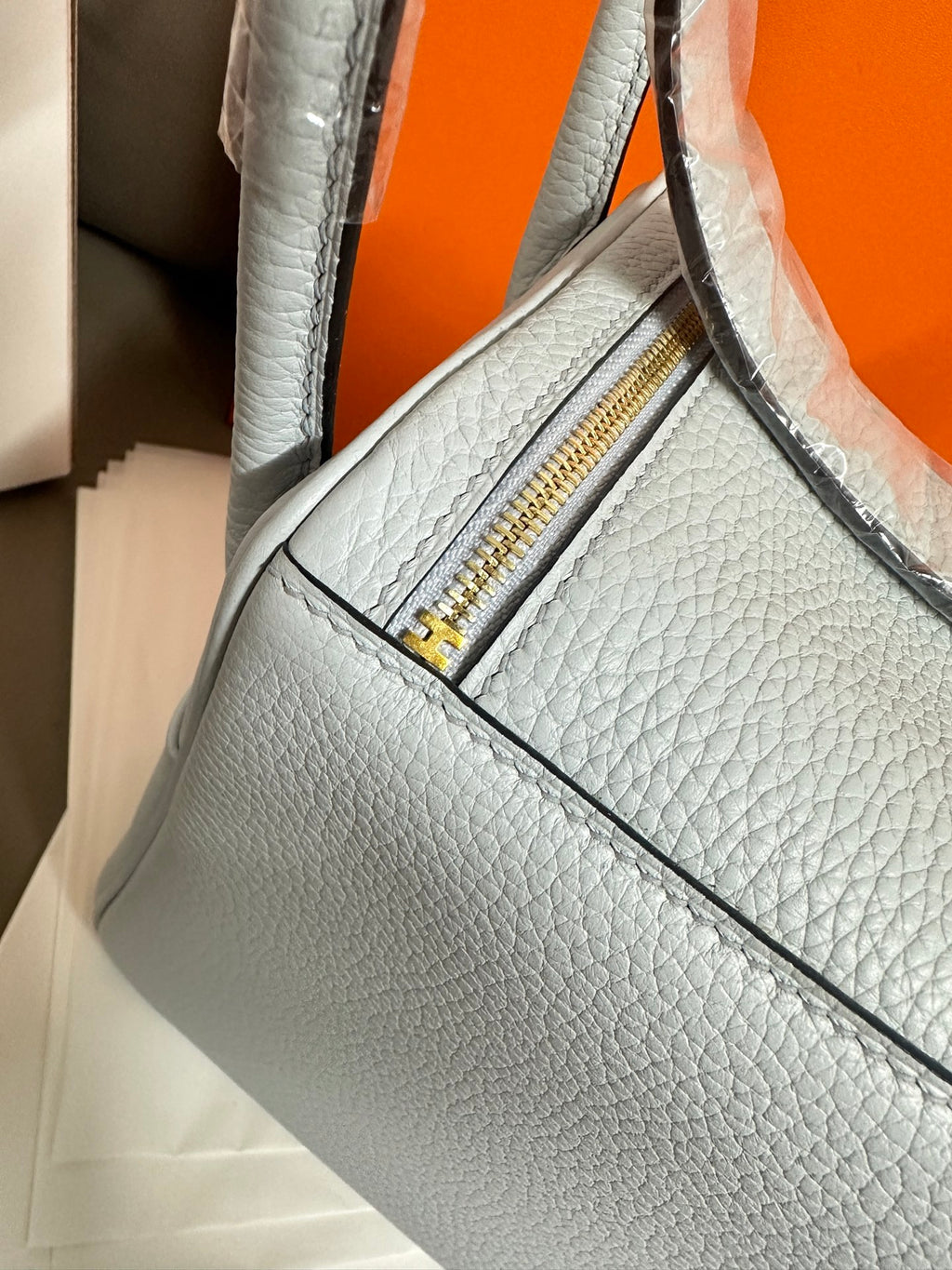 Light blue leather handbag with side zipper opening and gold zipper pull.